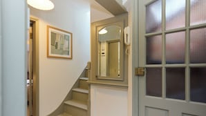 Un escalier avec une rampe, un tableau encadré au mur et une porte dotée de panneaux en verre dépoli.