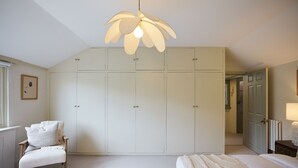Une chambre dotée d’une grande armoire, d’une chaise, d’un lit et d’un luminaire au plafond original.