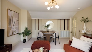 Un salon moderne comprenant une télévision, une table à manger avec des chaises, un canapé, une table basse et un grand miroir.