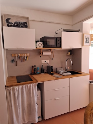 Eine kleine Küche mit Mikrowelle, Spüle und Holz Arbeitsplatte.