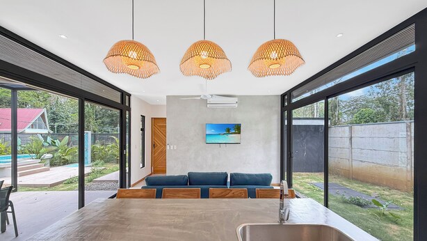 A modern kitchen with a large island, a built-in sink, and pendant lighting. - A Secluded Modern Villa with Private Pool, Jungle Oasis Bathtub & Beach Access (puerto viejo de talamanca)