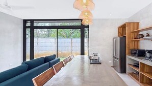 A modern kitchen with a large island, built-in appliances, and a dining area with a sofa. - A Secluded Modern Villa with Private Pool, Jungle Oasis Bathtub & Beach Access (puerto viejo de talamanca)