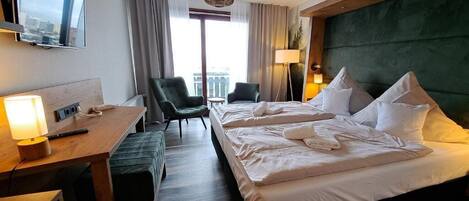 Habitación de hotel con cama, escritorio, silla, televisión y vista a la ciudad.