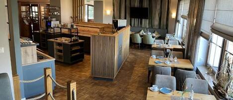 A restaurant with wooden flooring, a central bar area, and tables set for dining.