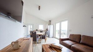 Un soggiorno moderno con un tavolino in legno, un divano in pelle marrone e un'area pranzo con un tavolo e sedie in legno.