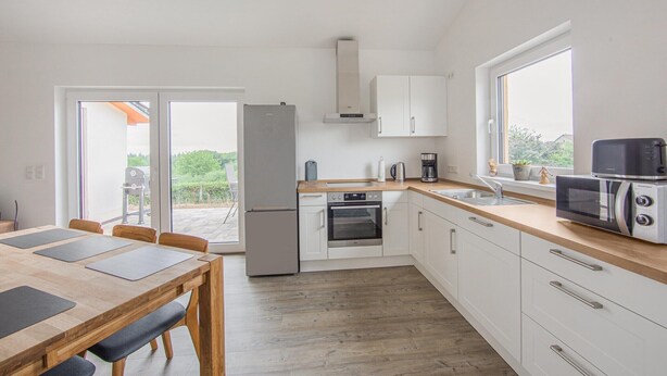 Una cucina moderna con zona pranzo, forno integrato, microonde e un'ampia finestra.