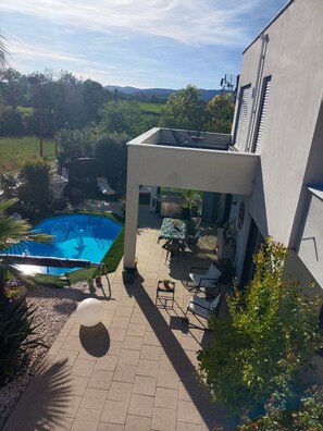 Ein modernes Haus mit Pool, Sitzgelegenheit im Freien und Blick auf die Landschaft.