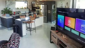 A modern living room with a flat-screen TV, a dining area, and a kitchen. - Spacious architect-designed villa in quiet location with tourist access PÉZENAS.BEZIERS.SETE.AGDE (Laurens)