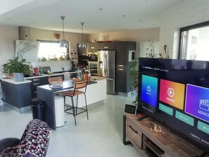Ein modernes Wohnzimmer mit Flachbildfernseher, Essbereich und Küche.