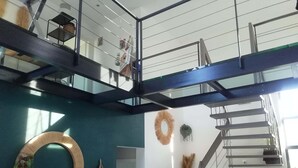A modern interior with a staircase, a circular wall decoration, and a hanging plant. - Spacious architect-designed villa in quiet location with tourist access PÉZENAS.BEZIERS.SETE.AGDE (Laurens)