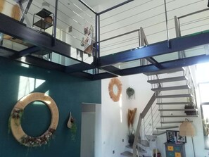 Ein modernes Interieur mit Treppe, einer runden Wanddekoration und einer hängenden Pflanze.