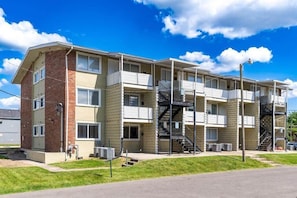Ein mehrstöckiges Apartmenthaus mit Backsteinfassade, mehreren Balkonen und einer zentralen Treppe.
