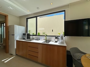 A modern kitchen with a refrigerator, coffee maker, and sink. - Chalé by Vila Manga Rosa (Tibau do Sul)