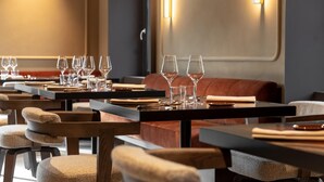 Un restaurante con varias mesas, sillas y copas de vino.