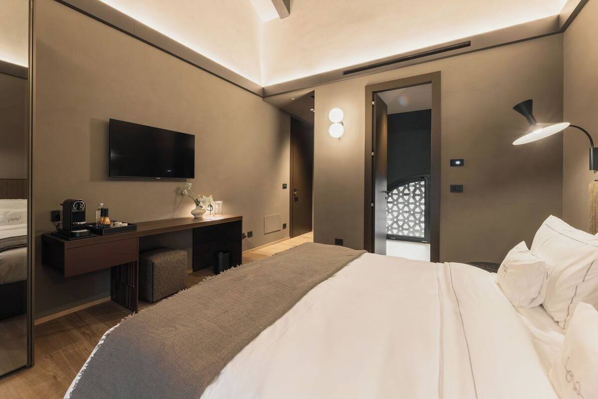 Moderni hotellihuone, jossa on sänky, työpöytä, televisio ja kylpyhuone.