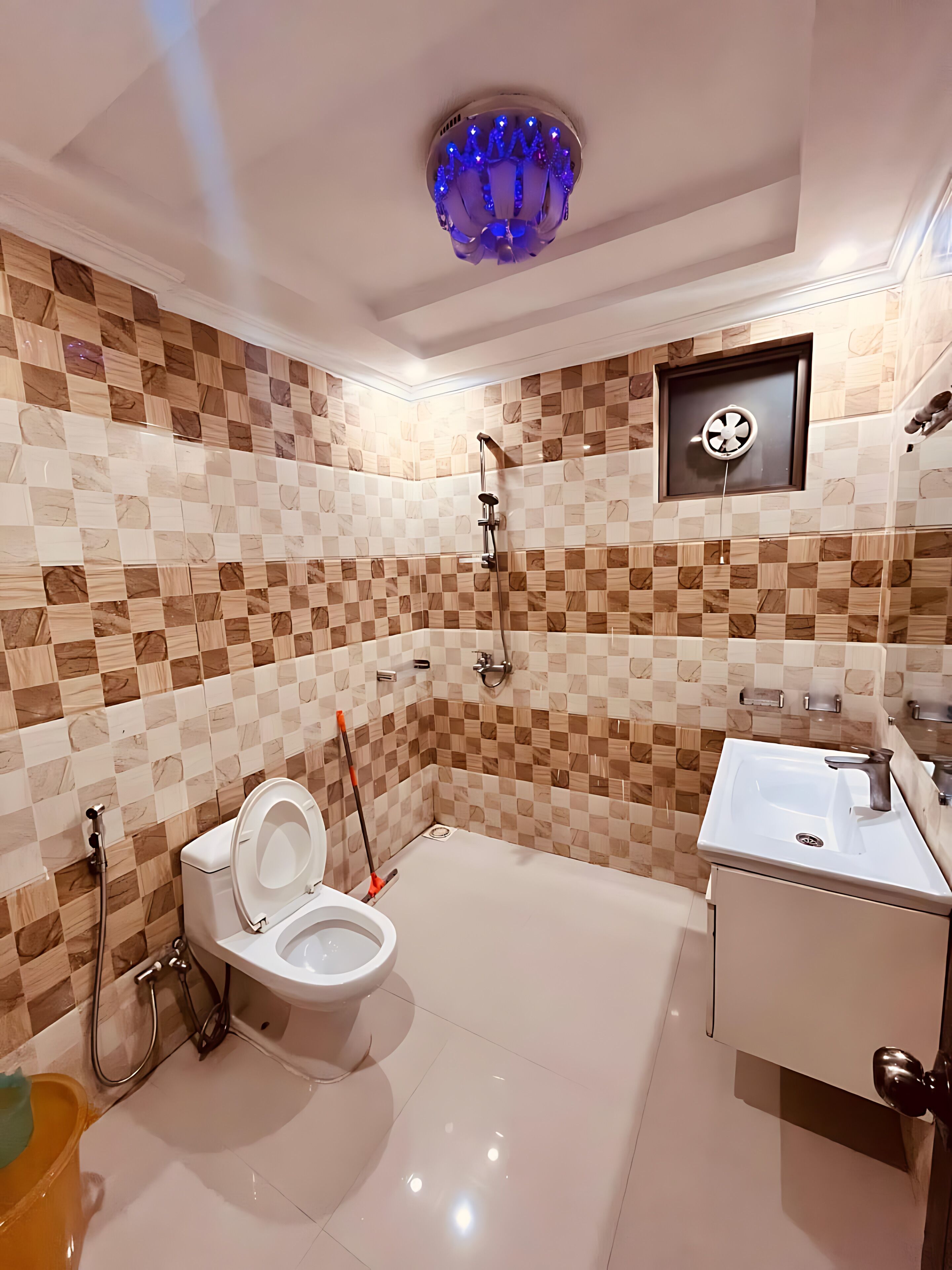 A bathroom with a checkered tile wall, a white toilet, a shower, and a sink.