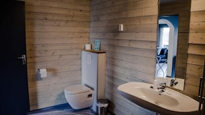 A bathroom with wooden panel walls, a white toilet, a sink, and a mirror. - Rondablikk (Nord-Fron)