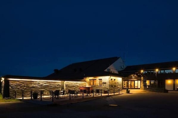 A building with a stone facade, a covered outdoor seating area, and a visible entrance.