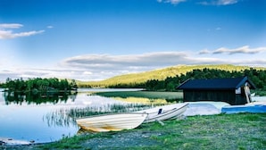 A calm lake with boats, a wooden dock, and a small cabin. - Rondablikk (Nord-Fron)
