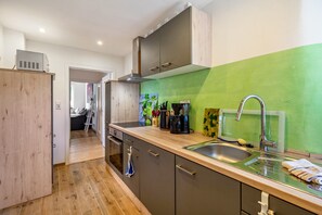 Une cuisine moderne dotée d’un plan de travail en bois, d’un évier en acier inoxydable et d’un mur d’accent vert.