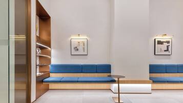 A modern waiting area with blue cushioned seating, a small table, and framed artwork on the walls.
