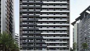 Un edificio de varios pisos con un diseño arquitectónico moderno, que presenta una cuadrícula de balcones y ventanas amplias.