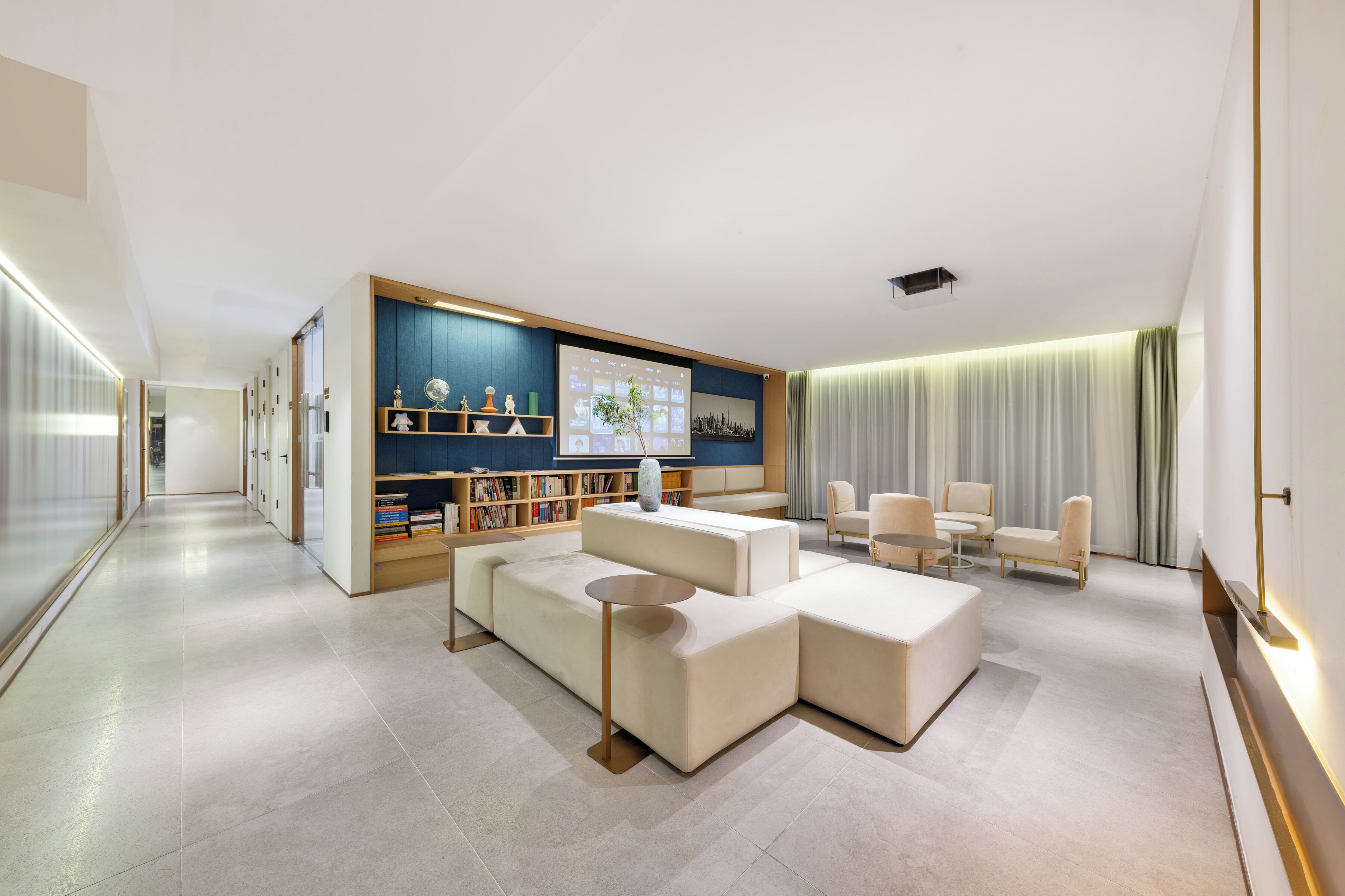 A modern living room with a sectional sofa, a coffee table, a bookshelf, and a flat-screen TV.