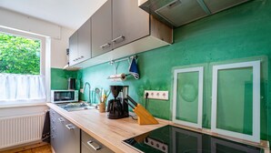 Une cuisine moderne dotée d’un plan de travail en bois, d’appareils électroménagers en acier inoxydable et d’un revêtement mural vert.