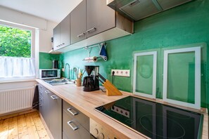 A modern kitchen with a wooden countertop, stainless steel appliances, and a green backsplash. - Upstairs Apartment in Husen’s Altenautal, Near Paderborn (Lichtenau)