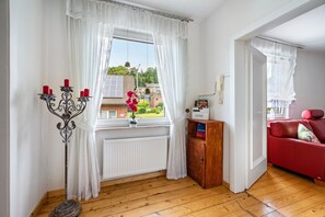 A room with a window, a red sofa, a wooden cabinet, and a candelabra with candles. - Upstairs Apartment in Husen’s Altenautal, Near Paderborn (Lichtenau)