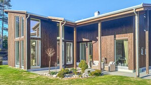 A modern house with large glass windows, a wooden exterior, and a well-maintained garden. - 5 bedroom nice home in Konsmo (Konsmo)