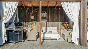 A covered outdoor seating area with a grill, wicker furniture, and potted plants. - 5 bedroom nice home in Konsmo (Konsmo)