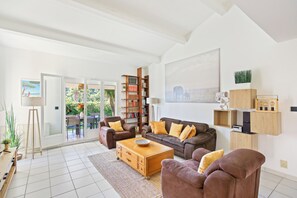 Ein Wohnzimmer mit einer Couch, Sesseln, einem Couchtisch, einem Bücherregal und einem Gemälde.