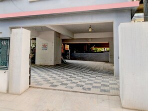 Entrada de hotel con mostrador de recepción, un cartel que indica que la recepción está en el primer piso y suelo de baldosas.