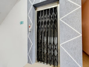 Una puerta con una reja de seguridad metálica, un detector de incendios y un cartel de indicaciones en la pared.