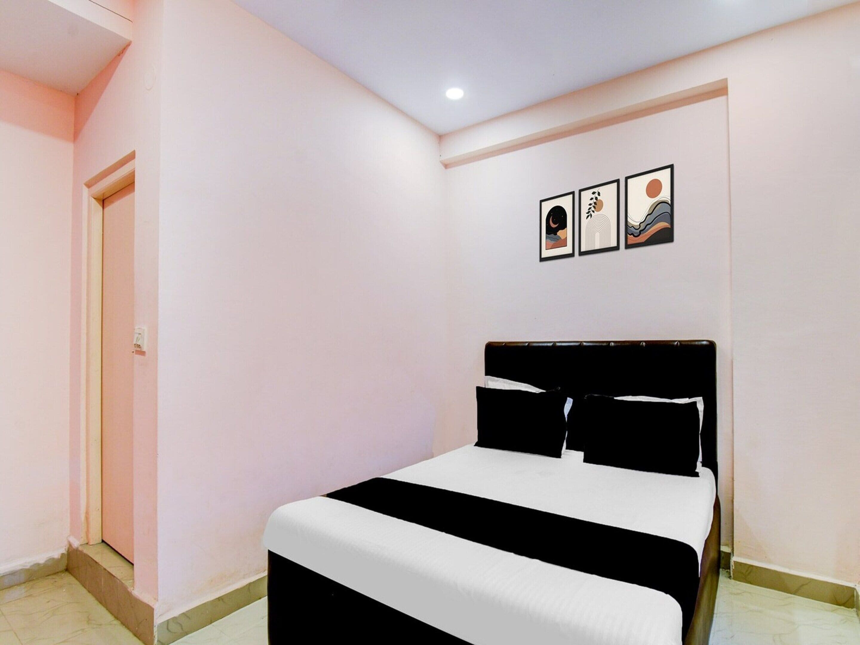 A bedroom with a bed, a door, and three framed pictures on the wall.