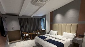 A modern hotel room with a large bed, a desk, a chair, and a wardrobe. - The Moonsoon Inn (Mussoorie)