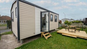 Une maison mobile de plain-pied dotée d’une porte coulissante, d’une petite terrasse et d’une table de pique-nique.