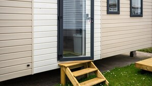Une maison mobile dotée d’une porte-fenêtre coulissante, d’une petite marche en bois et d’une fenêtre.