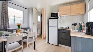 Une cuisine de taille réduite équipée d’un four à micro-ondes, d’un réfrigérateur et de meubles de rangement en bois.