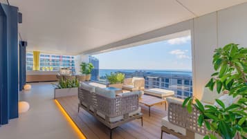 Een moderne woonkamer met een balkon, ingericht met banken en een salontafel, met uitzicht op een stadsbeeld.