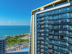 A high-rise hotel with multiple balconies, a pool area, and a view of the ocean. - Opus Batumi (Batumi)