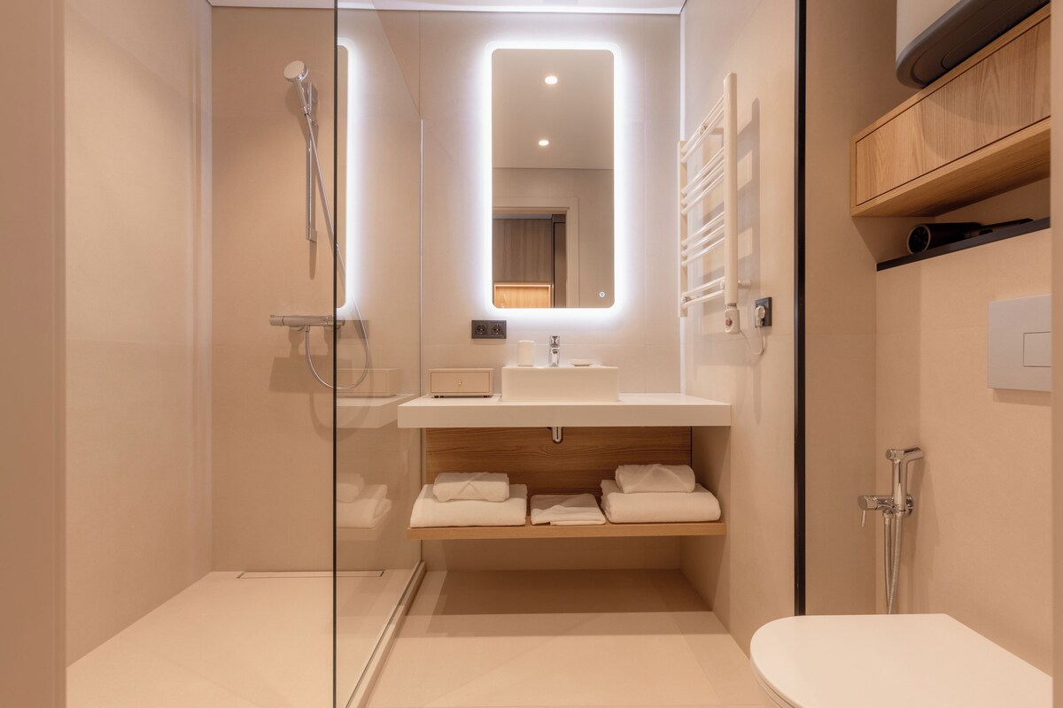 Un baño moderno con cabina de ducha de vidrio, tocador con espejo y un inodoro.