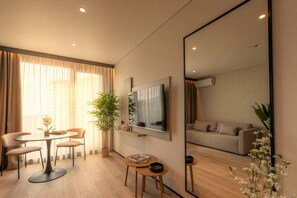 A modern living room with a round dining table, two chairs, a sofa, a TV, and a large mirror. - Opus Batumi (Batumi)