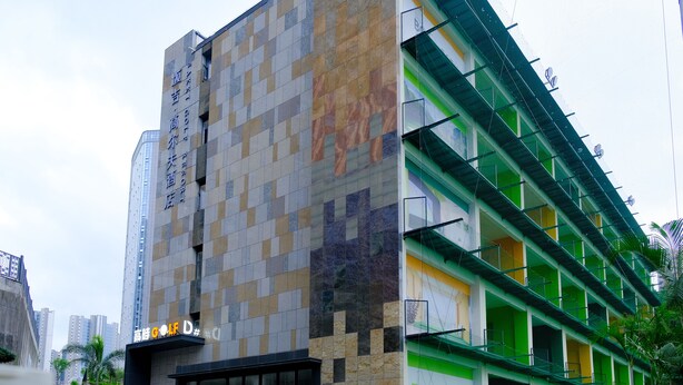 A multi-story building with a patterned facade, balconies, and a sign indicating a hotel. - Golf Suite Hotel (Shenzhen)