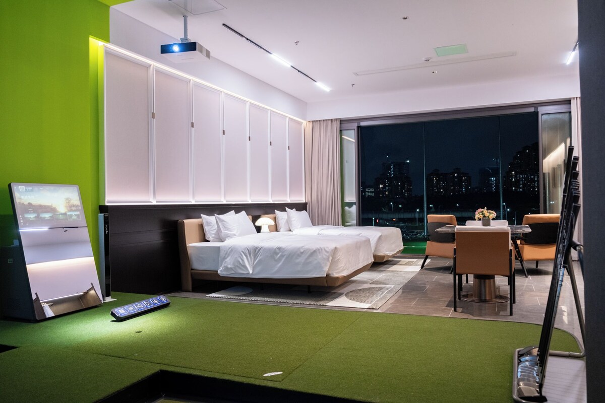 Quarto de hotel moderno com uma cama grande, uma escrivaninha e varanda com vista para a cidade.