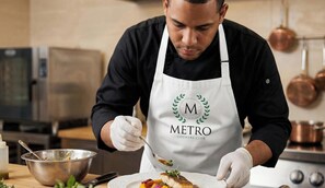 A person in a kitchen wearing a white apron with 'METRO COUNTRY CLUB' logo, preparing food. - Villa| BBQ |Daily Cleaning| Private Pool |Chef (Juan Dolio)