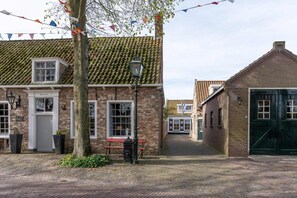 A traditional brick building with a tiled roof, a bench, and a lamp post. - Holiday home with garden in Aagtekerke | Dorpsplein 25 (Aagtekerke)