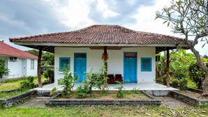 A single-story building with a tiled roof, blue shutters, and a small porch area. - Cozzy HEPI Bungalo Lovina Singaraja Bali (Buleleng)