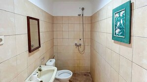 A small bathroom with a toilet, sink, and shower. - Cozzy HEPI Bungalo Lovina Singaraja Bali (Buleleng)